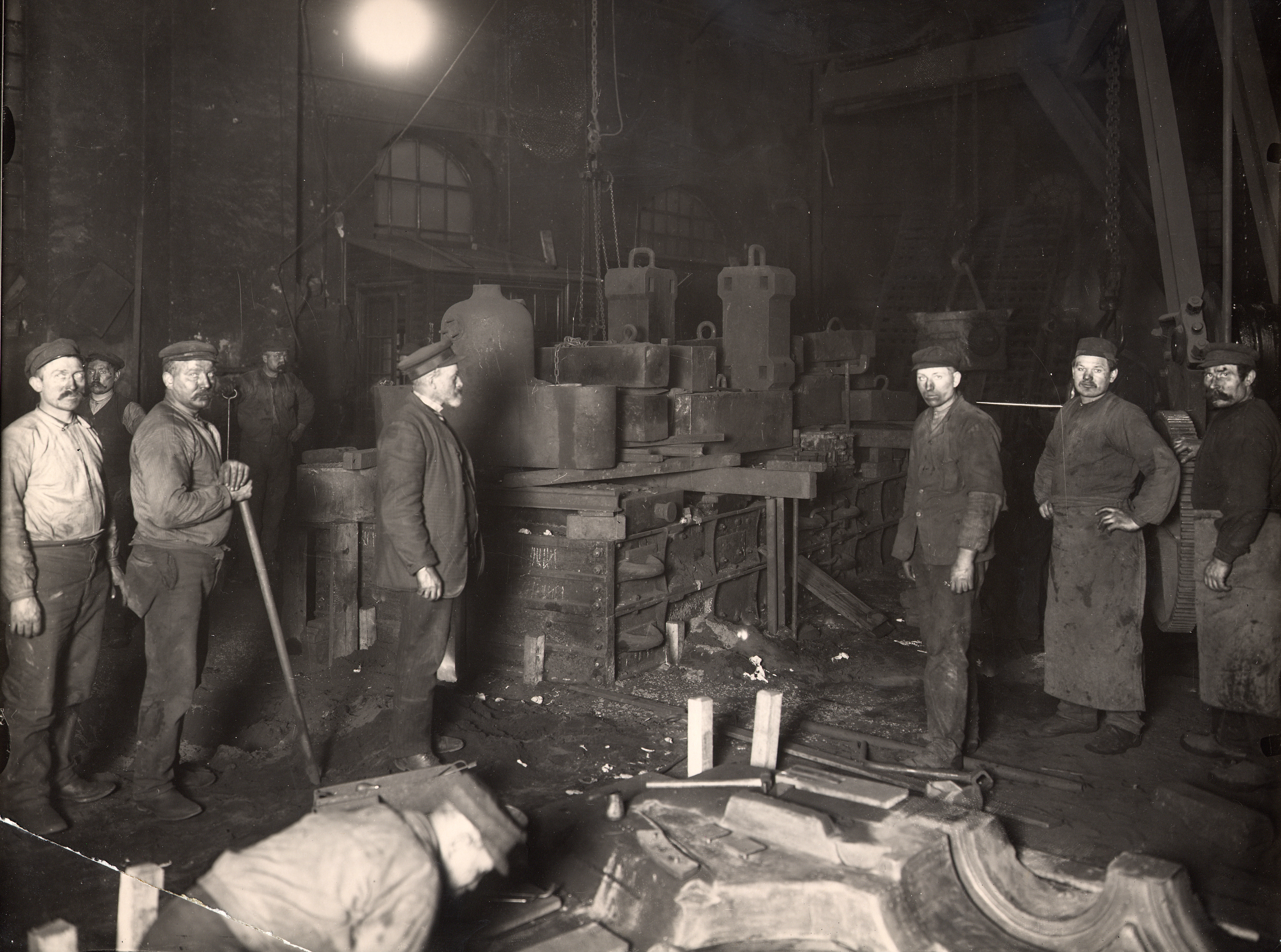Robotnicy w odlewni zakładów Bolinders w 1910 roku — przemysłowa hala pełna maszyn i form odlewniczych